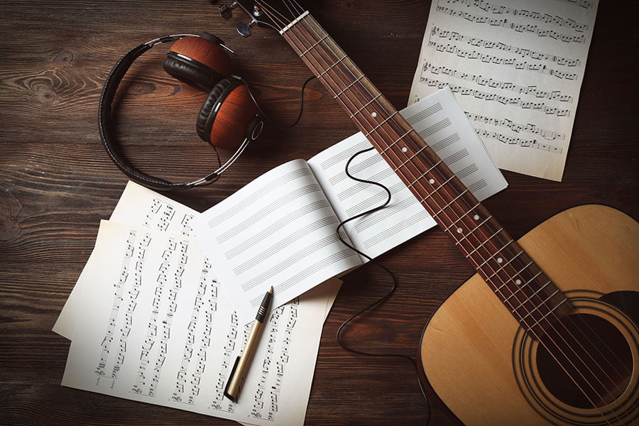 Noten, eine Gitarre und Kopfhörer: Hier ist jemand gerade dabei, einen Coversong einzustudieren.