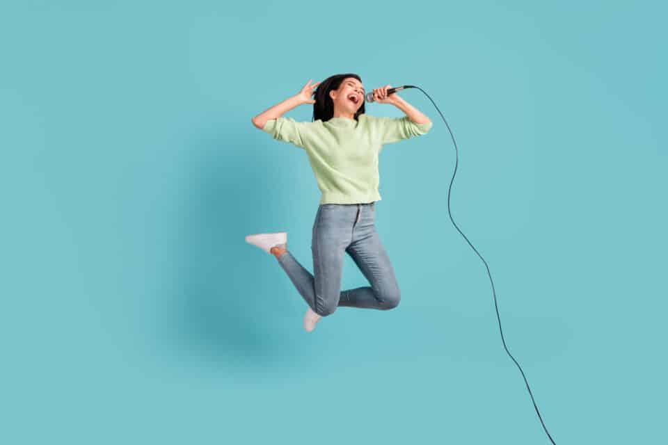 A woman with a microphone leaps into the air with delight - the image symbolises the successful singing of vocal riffs and runs